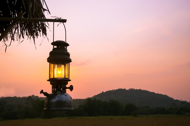 Alte Laterne hängen ein Holz in der Sonnenuntergangperiode.