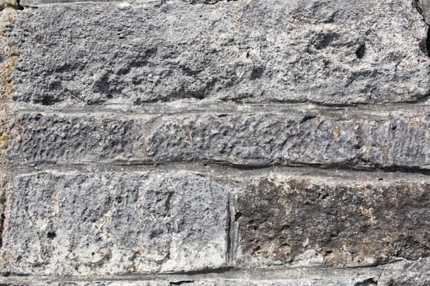 Alte Mauer aus großen Steinen und gebrochenen Ziegeln. Oberflächenhintergrund der rauen Blöcke der Weinlese