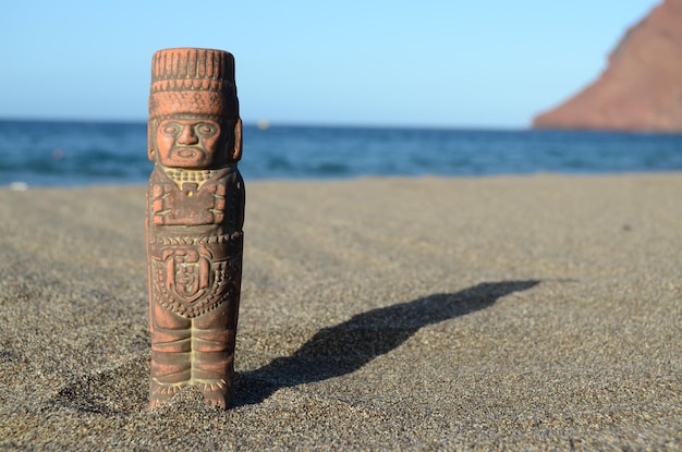 Foto alte maya-statue am sandstrand in der nähe des ozeans