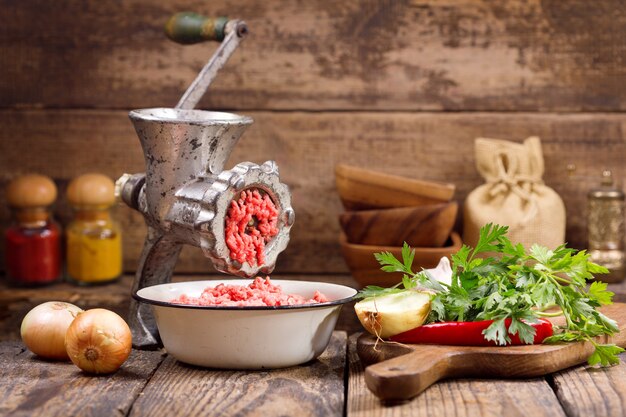 Alte Mühle mit Hackfleisch und Gemüse auf Holztisch