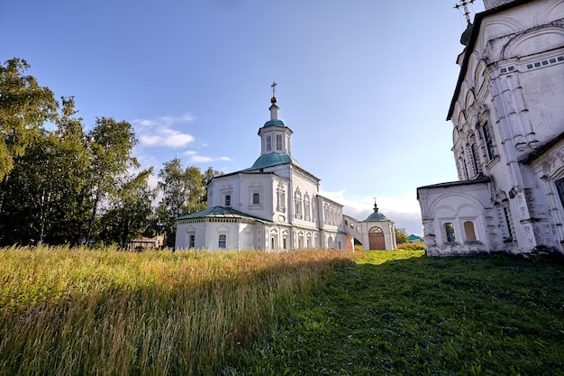 Alte orthodoxe Kirche im Dorf. Sommeransicht mit Blumenwiese. Sonniger Tag, blauer Himmel mit Wolken.