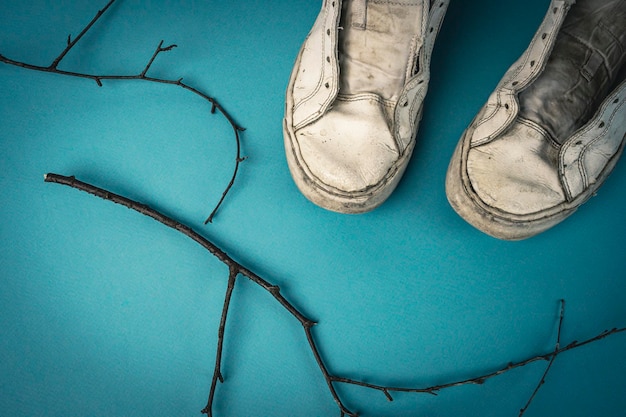 Alte ramponierte Women39s Turnschuhe ohne Schnürsenkel auf blauem Hintergrund