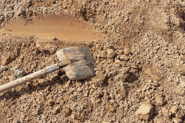 Alte rostige Schaufel im Sand am Gebäude