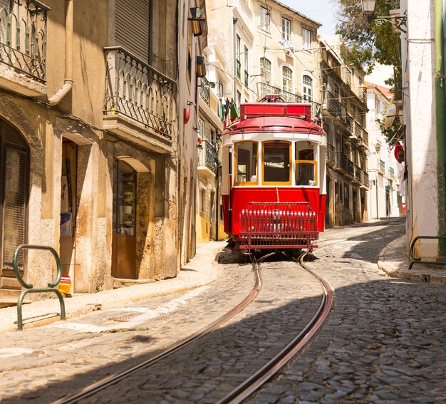 Alte rote Straßenbahn auf schmaler europäischer Straße an sonnigen Tagen