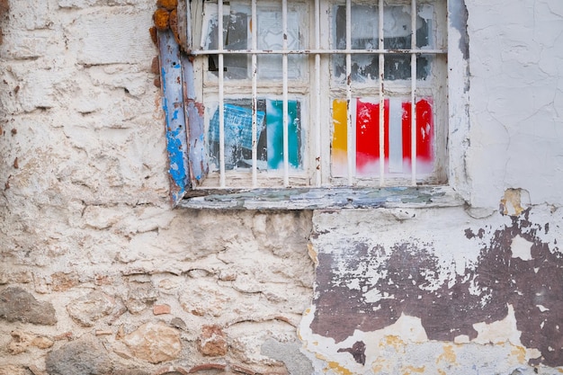 Alte, schmutzige Fenster mit rostigen Stangen und staubigem Glas an der Wand des verlassenen Hauses