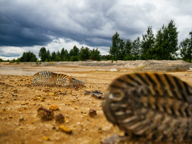 Foto alte schuhe und andere trümmer am ufer eines sandigen sees.