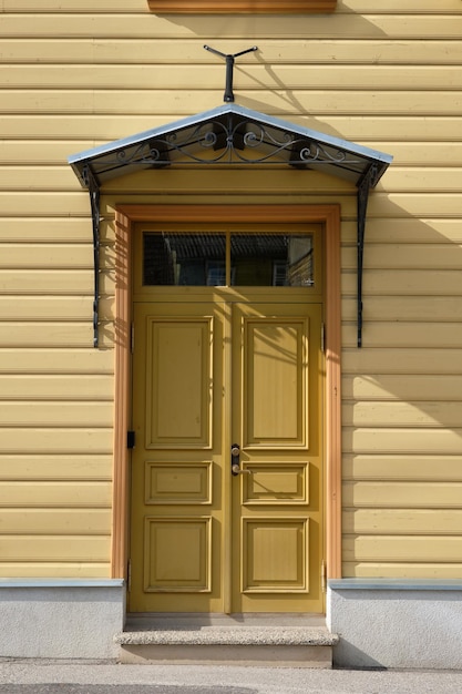 Alte senffarbene Holztüren Eingang zum Holzhaus mit gelber Farbe an den Wänden in Tartu Estland