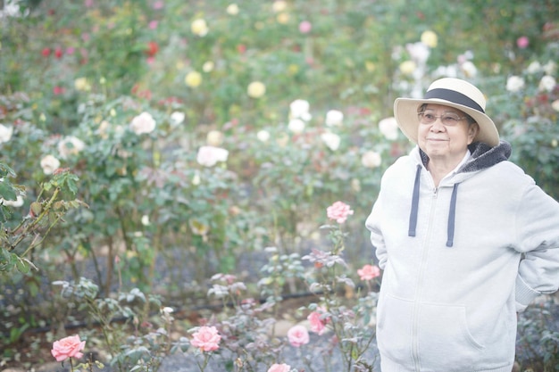 alte Seniorin, die sich im Rosengarten entspannt