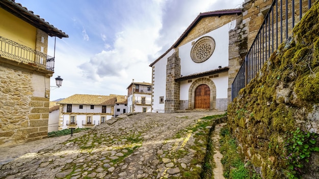 Alte Steinkirche neben traditionellen alten Häusern aus dem Dorf Candelario in Salamanca, Spanien