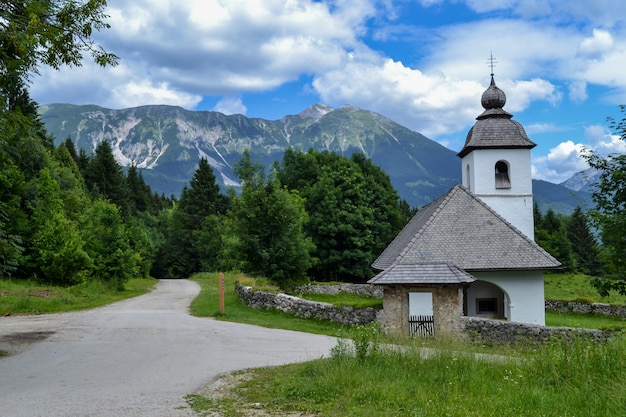 Alte Steinkirche und grüne Bergkette. Sonnige Landschaft mit blauem Himmel mit weißen Wolken.