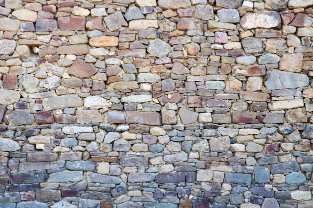 Alte steinmauer aus bunten steinen als hintergrund oder kulisse