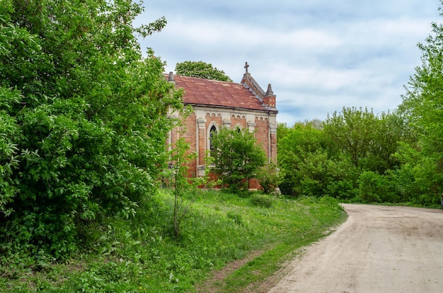 Alte verlassene Kirche mit roten Backsteinen auf einem Hintergrund von Bäumen