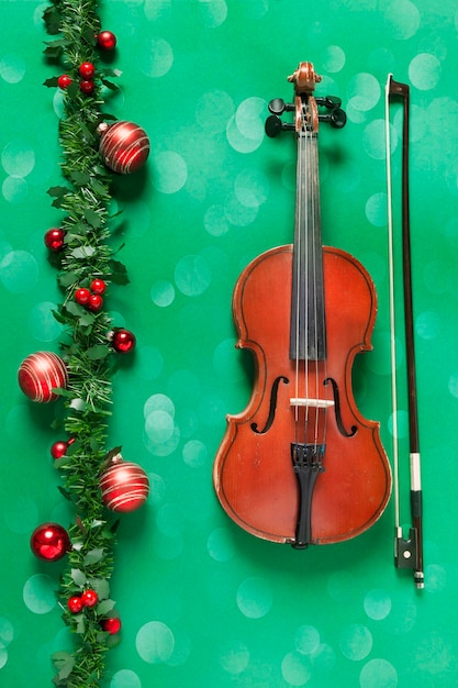 Alte Violine und schöne rote Weihnachtsdekoration auf grünem Hintergrund Konzept des Weihnachten-neuen Jahres Draufsichtnahaufnahme