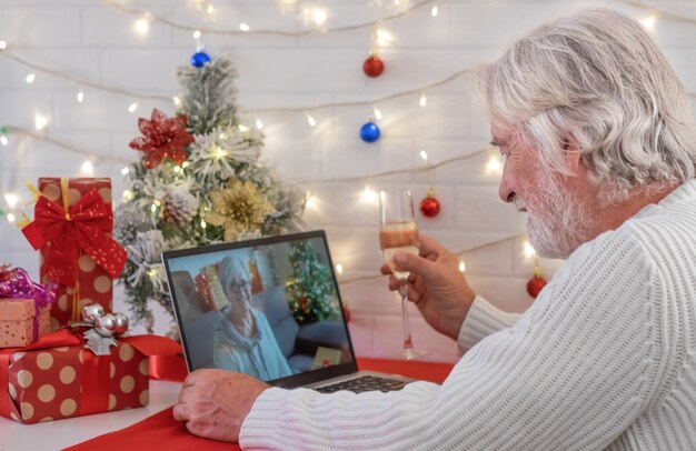 Alter älterer Mann mit Laptop für Videoanrufe mit entfernten Leuten Er feiert Weihnachten