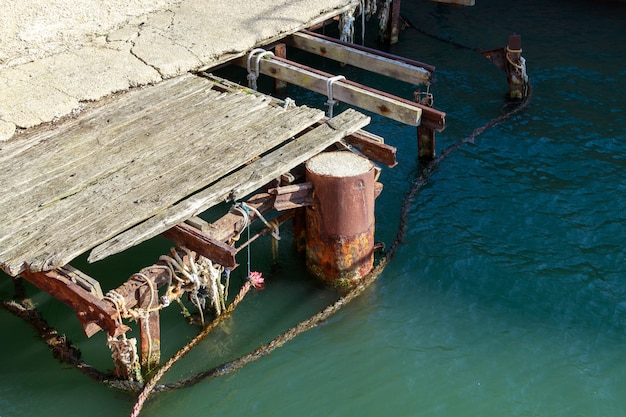 Alter beschädigter hölzerner Steg am Seehafen