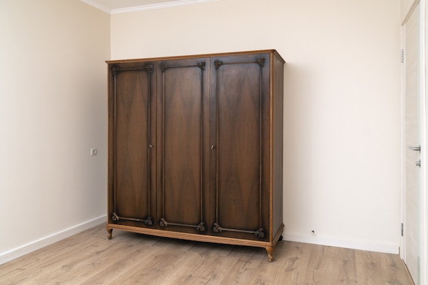 Alter brauner Holzschrank in einem modern renovierten Wohnzimmer mit gemalter Tapete