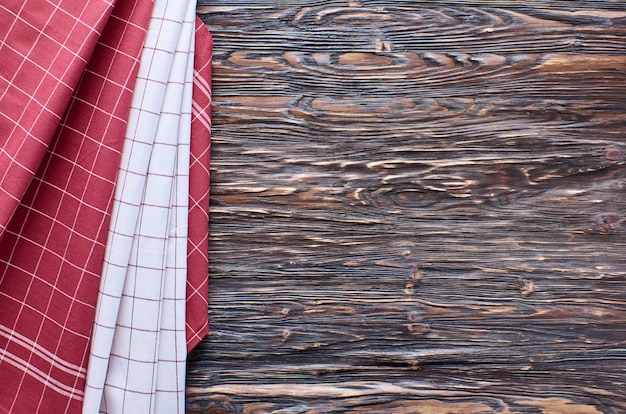 Alter dunkler hölzerner Hintergrund. Holztisch mit roten und weißen Küchentüchern