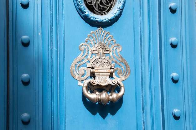 Alter Eisenring-Chrom-Silber-Klopfer an Vintage-Holz-Retro-blauer Tür zum Klopfen an die Fassade eines klassischen europäischen Hauses