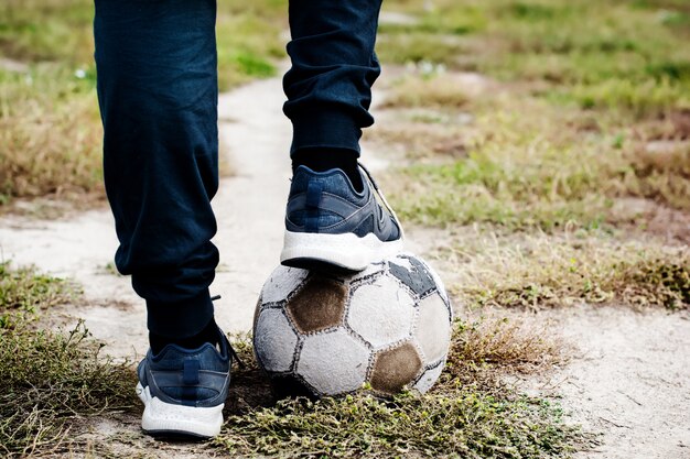 Alter Fußball mit seinen Füßen auf dem Fußballplatz. Selektiver Fokus.