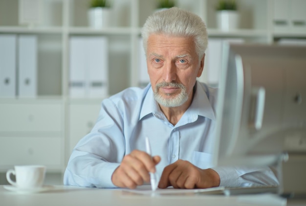 Alter Geschäftsmann mit einem Laptop, der im Büro arbeitet