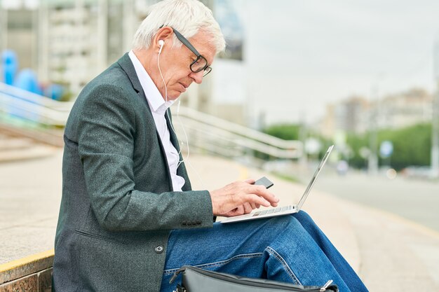 Alter Geschäftsmann mit Laptop auf Treppen