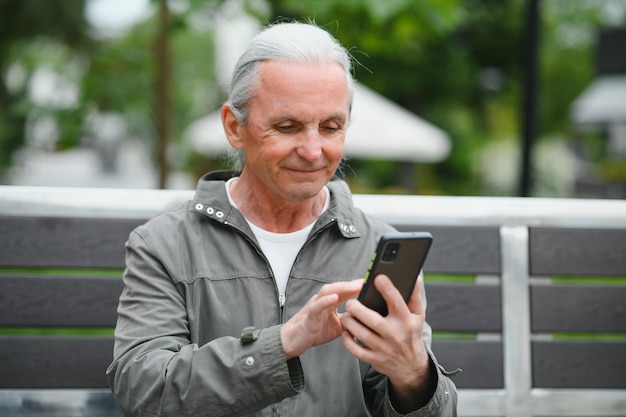 Alter grauhaariger Mann ruht sich auf der Bank im Sommerpark aus