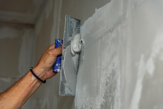 alter Handarbeiter mit Wandpflasterwerkzeugen renoviert ein Haus
