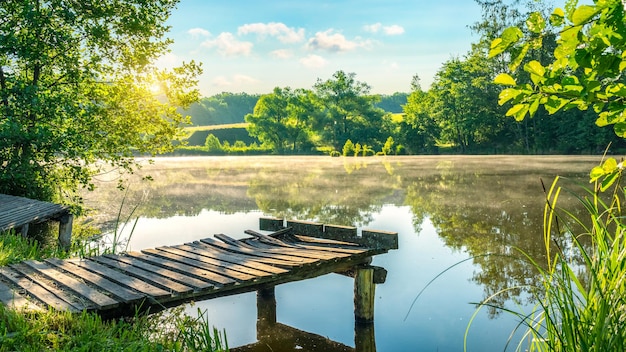 Alter hölzerner Angelsteg am Fluss am nebligen Morgen