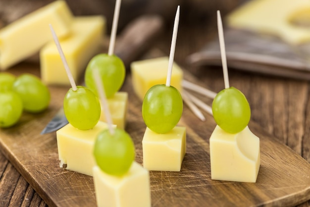 Alter Holztisch mit Käseblöcken und Trauben Partyfood