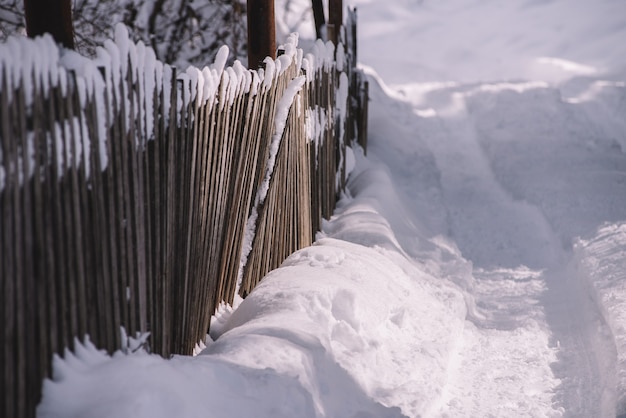 Alter Holzzaun am verschneiten und sonnigen Morgen