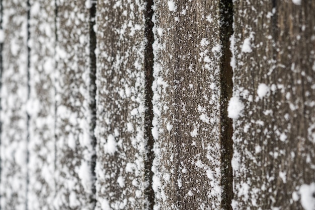 Alter Holzzaun. Auf dem Zaun liegen Schneeflocken