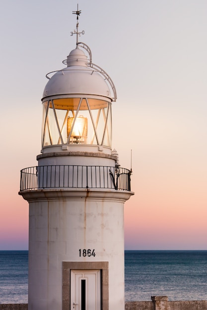 alter Leuchtturm an der Küste mit einem schönen Sonnenuntergang im Hintergrund