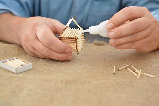 Foto alter mann beschäftigt sich mit handarbeit leimhaus mit streichhölzern bauträume handgefertigt freier platz handarbeit hobby