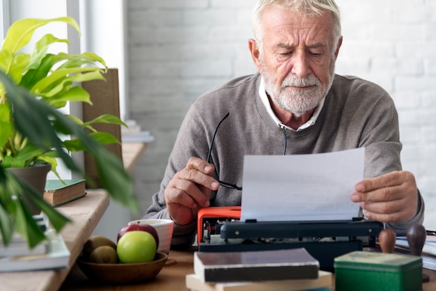 Alter Mann, der auf einer Schreibmaschine schreibt