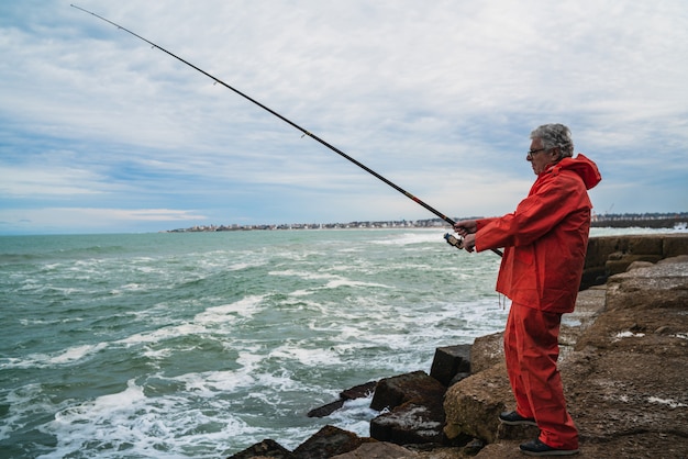 Alter Mann, der im Meer fischt.