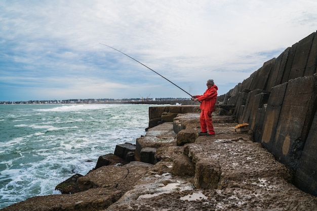 Alter Mann, der im Meer fischt.