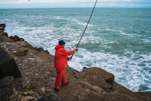 Alter Mann, der im Meer fischt.