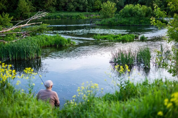 Alter Mann, der tagsüber im Sommer mit einem Freund an einem Fluss fischt, mit selektivem Fokus