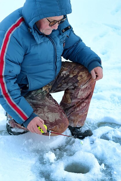 Alter Mann der Wintersaison, der auf einem See fischt