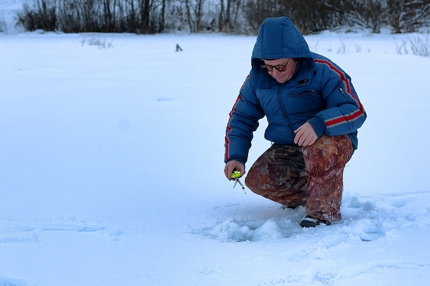 Alter Mann der Wintersaison, der auf einem See fischt