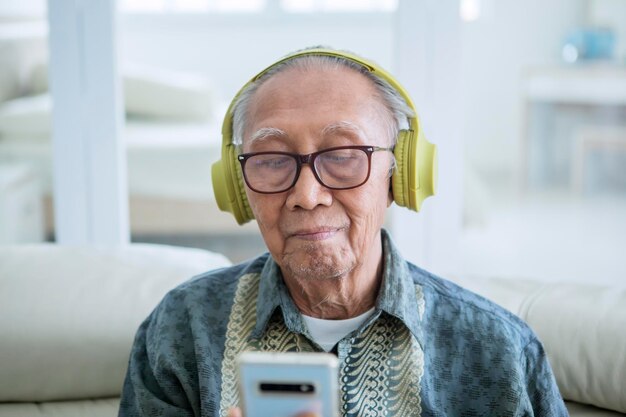 Alter Mann genießt Musik mit einem Telefon