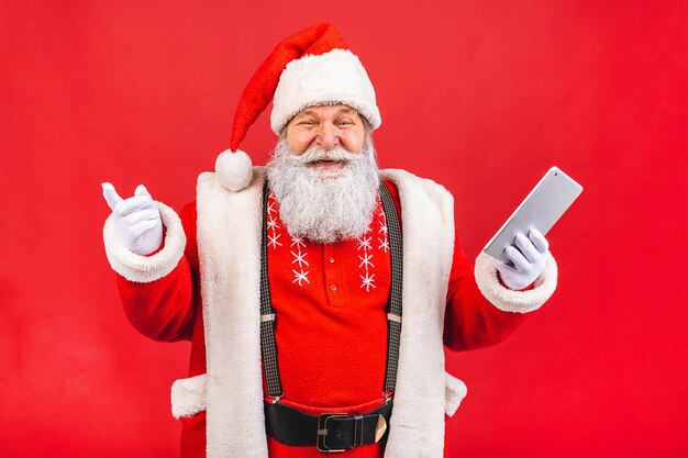 alter Mann im Weihnachtsmannkostüm, das eine Tafel lokalisiert auf rotem Hintergrund hält