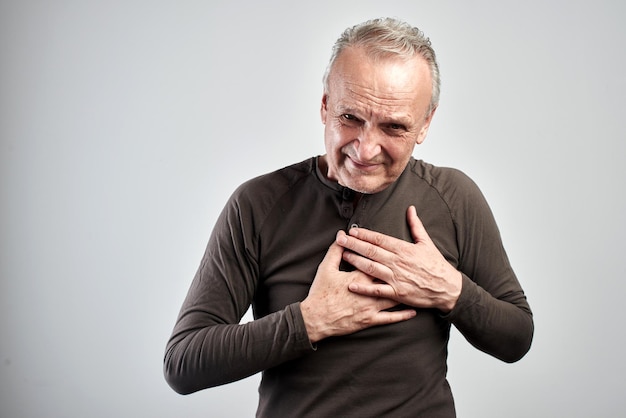 Alter Mann packte krankes Herz isoliert auf weißem Hintergrund Herzinfarkt Schlaganfall senile Krankheit Konzept