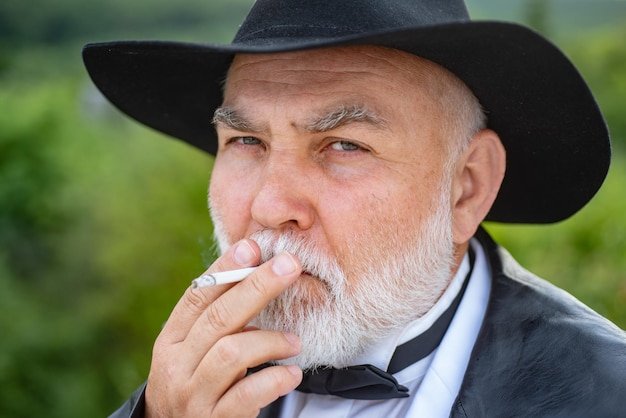 Alter Mann raucht Zigarette attraktiver älterer reifer Mann Gesicht der Seniorenmode Nahaufnahme