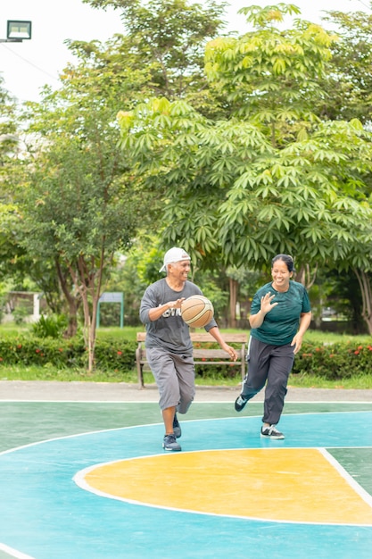 Alter Mann und Frau, die im BangYai Park Nonthaburi so glücklich Basketball spielen