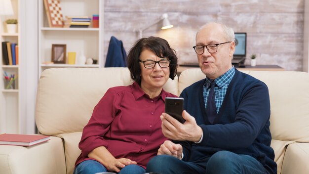 Alter Mann und Frau führen einen Videoanruf mit ihrem Smartphone. Älteres Ehepaar mit moderner Technologie