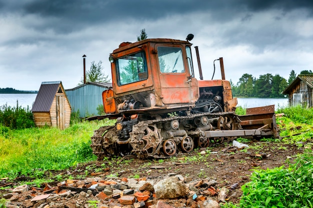 Alter schmutziger traktor durch den fluss in einer rustikalen landschaft.