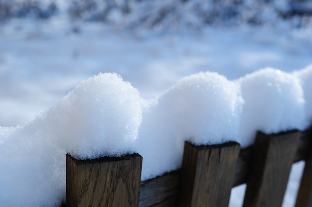 Alter schneebedeckter Zaun im Dorf im Weihnachtswinter