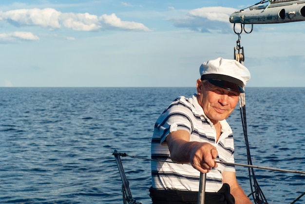 Alter Seemann auf seinem Segelboot vor einer Meereslandschaft