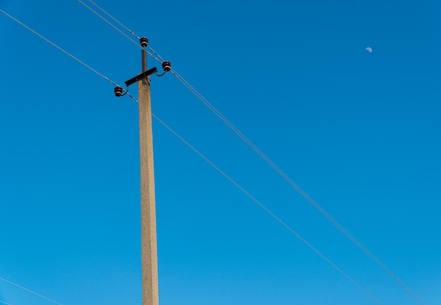 Alter Strommast mit Drähten für den Stromverkehr mit klarem blauem Himmel. Strommast.